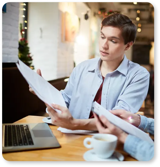 Two people sitting at a table looking at papers discussing their online presence for their business, considering the services of professional content writing agencies.