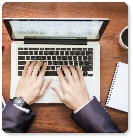 A man from ProntoWriters typing on a laptop, fuelled by a cup of coffee, working to boost online presence for content writing agencies.